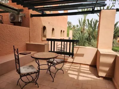 a patio with a table and chairs on a balcony at Suite dans la palmeraie refaite à neuf grande Terrasse Dar Dmana in Marrakech