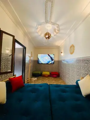 a living room with a blue couch and a television at Private Riad 3ch Salon, Terrasse avec Jacuzzi , à Jemaa El Fna in Marrakech