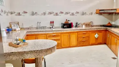 a kitchen with wooden cabinets and a granite counter top at Appartement Marrakech avec piscine privée in Marrakech