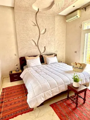 a bedroom with a large white bed and a rug at Appartement Marrakech avec piscine privée in Marrakech