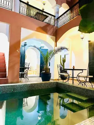 a swimming pool in a house with a table and chairs at Riad Dar Lilas in Marrakech