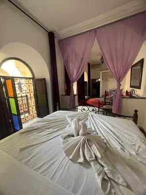 a white bed with a dress on top of it at Riad el Adraoui in Marrakech