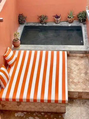 a swimming pool with an orange and white striped tub at Riad Le Petit Bacha in Marrakech