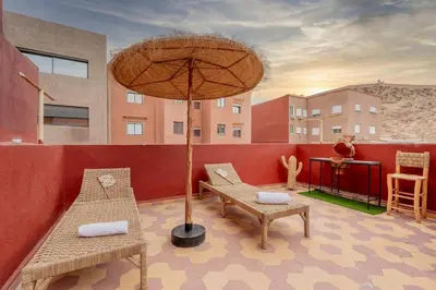 a patio with two chairs and a table and an umbrella at Rooftop centre ville Marrakech in Marrakech