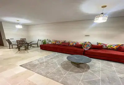 a living room with a red couch and a table at Appartement Prestigia Golf City Marrakech - Porte Agate - Gated community Rez-de-Jardin in Marrakech
