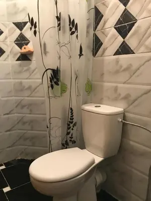 a white toilet in a bathroom with black and white tiles at Appartement 7 min de l'aéroport de Marrakech in Marrakech