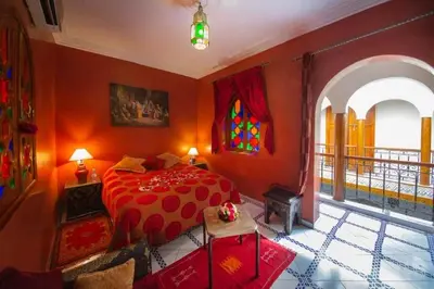 a bedroom with a bed with red walls and a window at La lune de Marrakech Riad in Marrakech