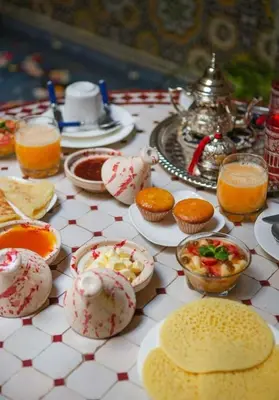 a table with cups and plates of food and drinks at La lune de Marrakech Riad in Marrakech