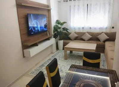a living room with a couch and a tv at Nour 5 marrakech in Marrakech