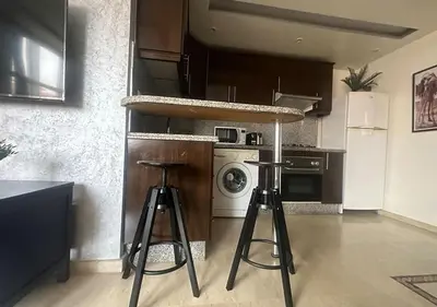 a kitchen with two bar stools and a refrigerator at Appartement agréable en plein coeur de Marrakech pour 2 à 4 Personnes in Marrakech
