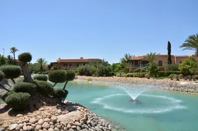 a fountain in the middle of a pool of water at Palmeraie Stay - Pool & Lake in Marrakech