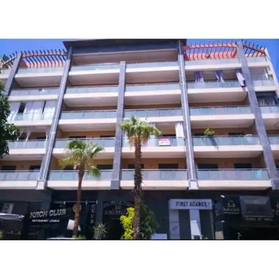 a tall building with palm trees in front of it at Gueliz budget Stay in Marrakech