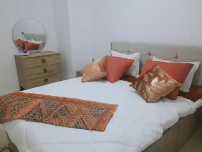 a bedroom with a white bed with pillows and a mirror at OASIS PALM MARRAKECH APARTMENT- 5 Piscines in Marrakech