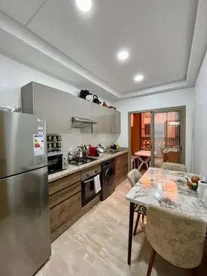 a kitchen with a stainless steel refrigerator and a table at Bel Appartement à Marrakech en Résidence avec Piscine - Fibre & Netflix in Marrakech