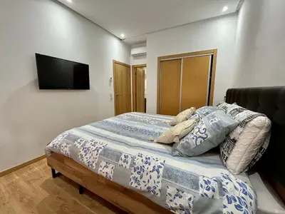 a bedroom with a bed with a tv on the wall at Bel Appartement à Marrakech en Résidence avec Piscine - Fibre & Netflix in Marrakech