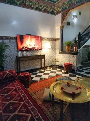 a living room with a table and a fireplace at Riad Tesnime in Marrakech