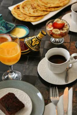 a table topped with plates of food and a cup of coffee at Riad Dollar Des Sables & Spa in Marrakech
