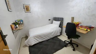 a small room with a bed and a desk and a chair at Appartement B à 7min de l’aéroport de Marrakech in Marrakech