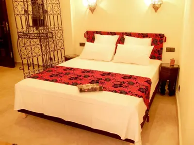 a bedroom with a large bed with a red blanket and white pillows at Riad Signature in Marrakech