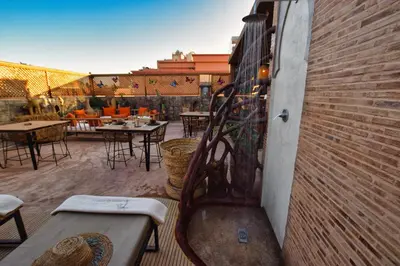 a patio with tables and chairs and a brick wall at Riad La Petite Majorelle in Marrakech