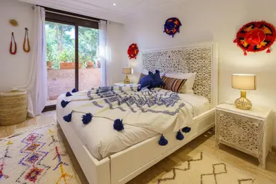 a bedroom with a white bed with blue accents at Luxueux 138 m2 avec piscine in Marrakech