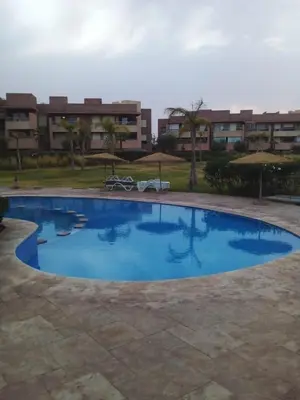 a large blue swimming pool with buildings in the background at Prestigia Agate golf Piscine Marrakech in Marrakech