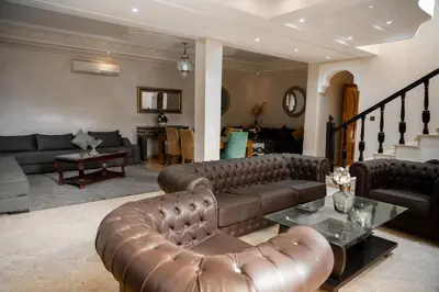 a living room with a leather couch and a table at villa 5 chambres pour famille avec piscine & parking in Marrakech