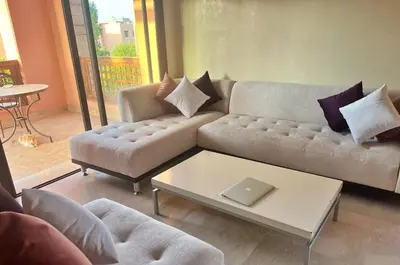 a living room with a couch and a table with a laptop at Luminous apartment with pool view in Marrakech