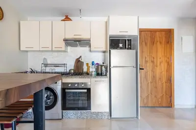 a kitchen with white cabinets and a white refrigerator at Appartement pour les familles , superbe vue sur la piscine in Marrakech