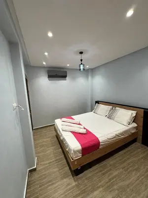 a bedroom with a bed with white sheets and red blanket at Bel appartement à louer à Marrakech targa in Marrakech