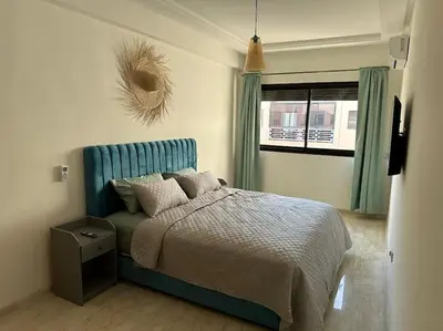 a bedroom with a bed with a blue headboard and a window at Charm Apartment in Marrakech in Marrakech