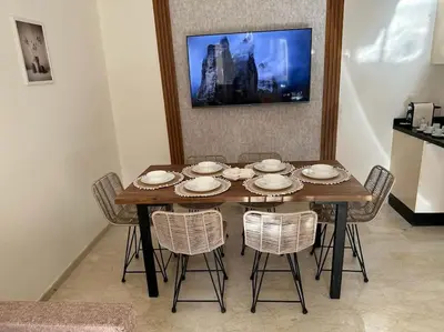 a dining room table with chairs and a television on a wall at Charm Apartment in Marrakech in Marrakech
