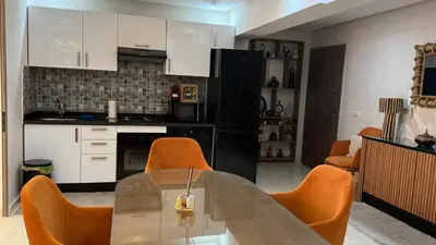 a kitchen with a glass table and orange chairs at LA FINCA DE MARRAKECH in Marrakech