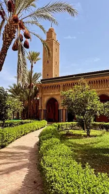 a building with a clock tower in a park at Riad lalla aicha in Marrakech