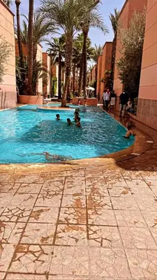 a group of people swimming in a large swimming pool at Riad lalla aicha in Marrakech