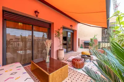 a patio with a table and an orange building at Le Jasmin - Appartement Authentique à Gueliz in Marrakech