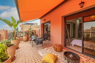 an orange house with a balcony with a table and chairs at L'Atlas - Appartement Authentique à Gueliz in Marrakech