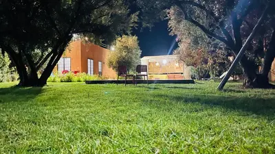 a park with a building and a bench in the grass at Le Domaine des Oliviers in Marrakech