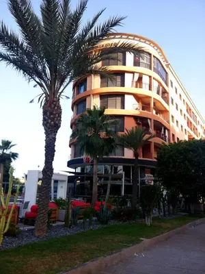 a tall building with a palm tree in front of it at Votre appartement d'exception in Marrakech