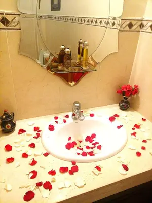 a bathroom sink with red flowers on a counter at Votre appartement d'exception in Marrakech
