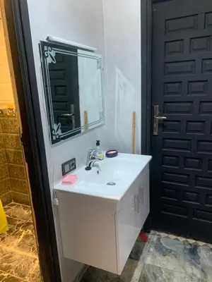 a bathroom with a sink and a mirror and a door at Familiale Chambre calm wifi Hanae in Marrakech