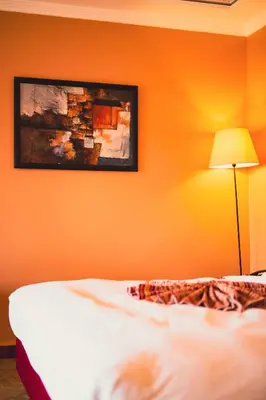 a bedroom with an orange wall with a bed and a lamp at Palais Jena in Marrakech