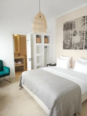 a white bedroom with a large bed and a blue chair at Riad Coconut in Marrakech
