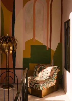 a room with a couch in front of a mural at Riad Pompon in Marrakech