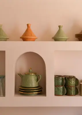 a shelf with different colored vases and bowls on it at Riad Pompon in Marrakech