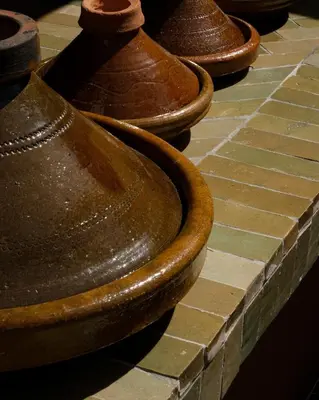 a row of brown vases sitting on a brick floor at Riad Pompon in Marrakech