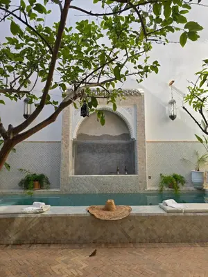 a straw hat sitting on a bench next to a swimming pool at RIAD SAMAH in Marrakech