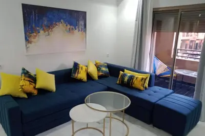 a blue couch with yellow pillows and a table at 1 Bed Apartment - Balcony Wifi Parking in Marrakech