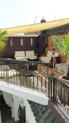 a balcony of a house with a table and chairs at Ryad Petit Palmier in Marrakech