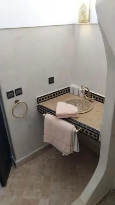 a bathroom with a sink and a towel rack at Ryad Petit Palmier in Marrakech
